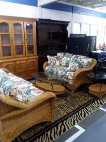 Photo of vendor table displaying miscellaneous furniture, wooden cabinet and couches and end tables for sale.